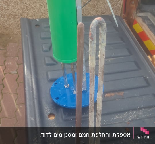 רכיבי דוד שמש על משטח, כולל גוף חימום ומיכל ירוק.